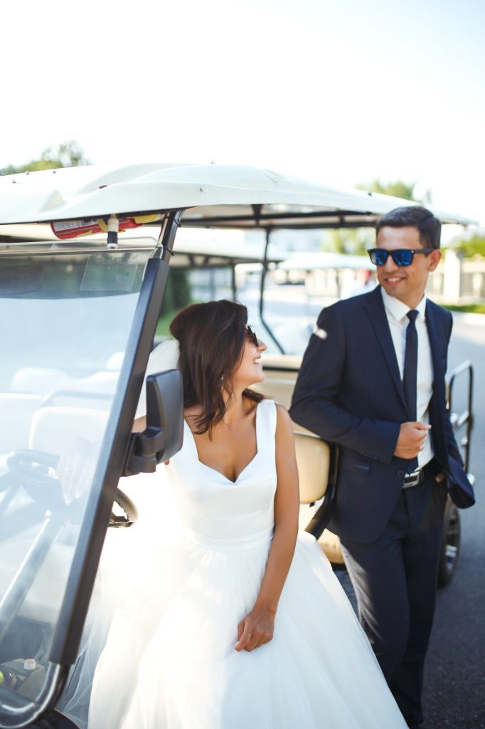 Luxury elegant wedding couple kissing, embracing near car for golf. Together. Young family. Marriage
